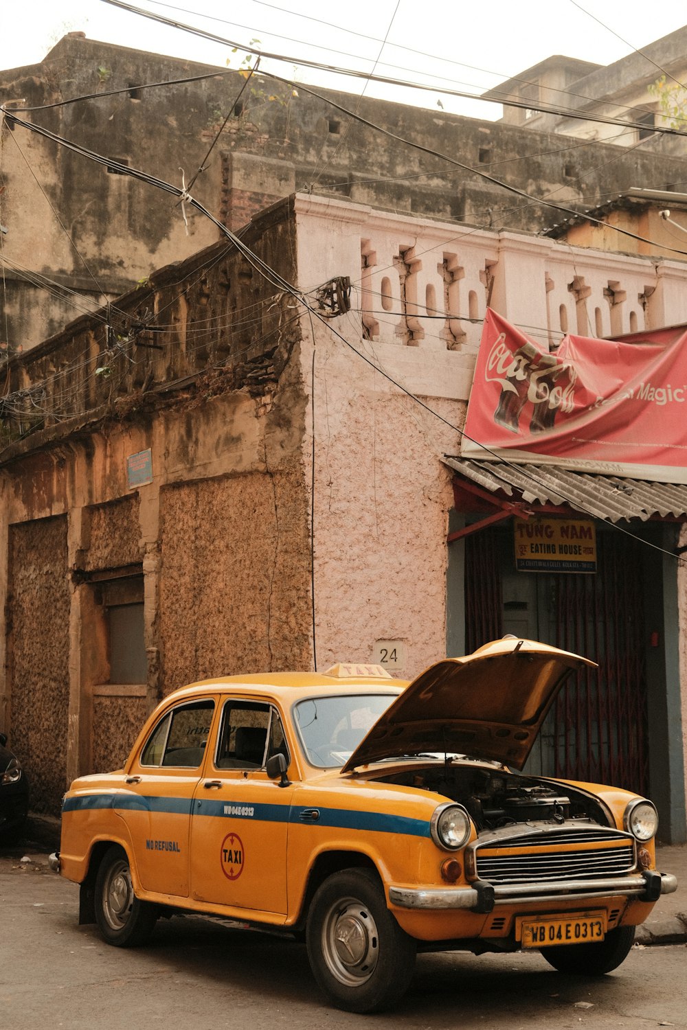 a yellow car with a hood open parked in front of a building