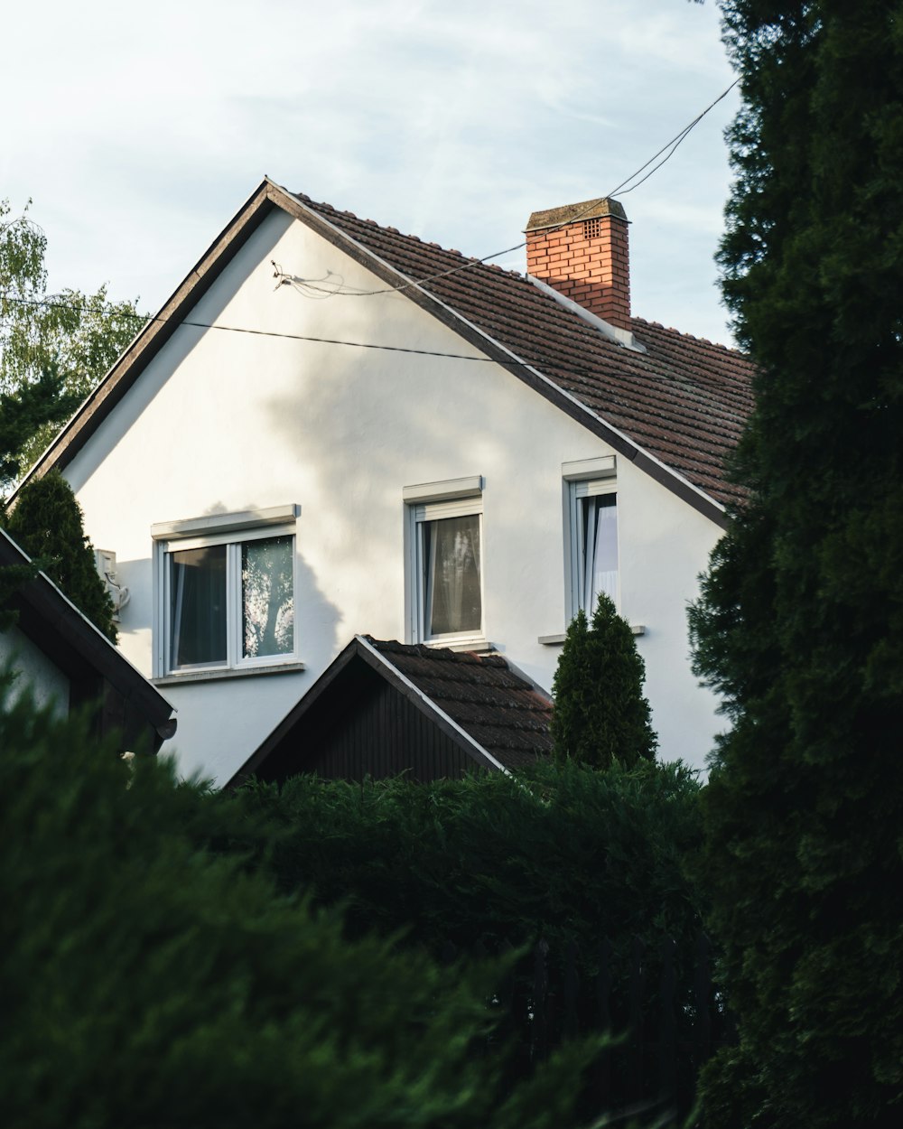 a white house with two windows and a red roof