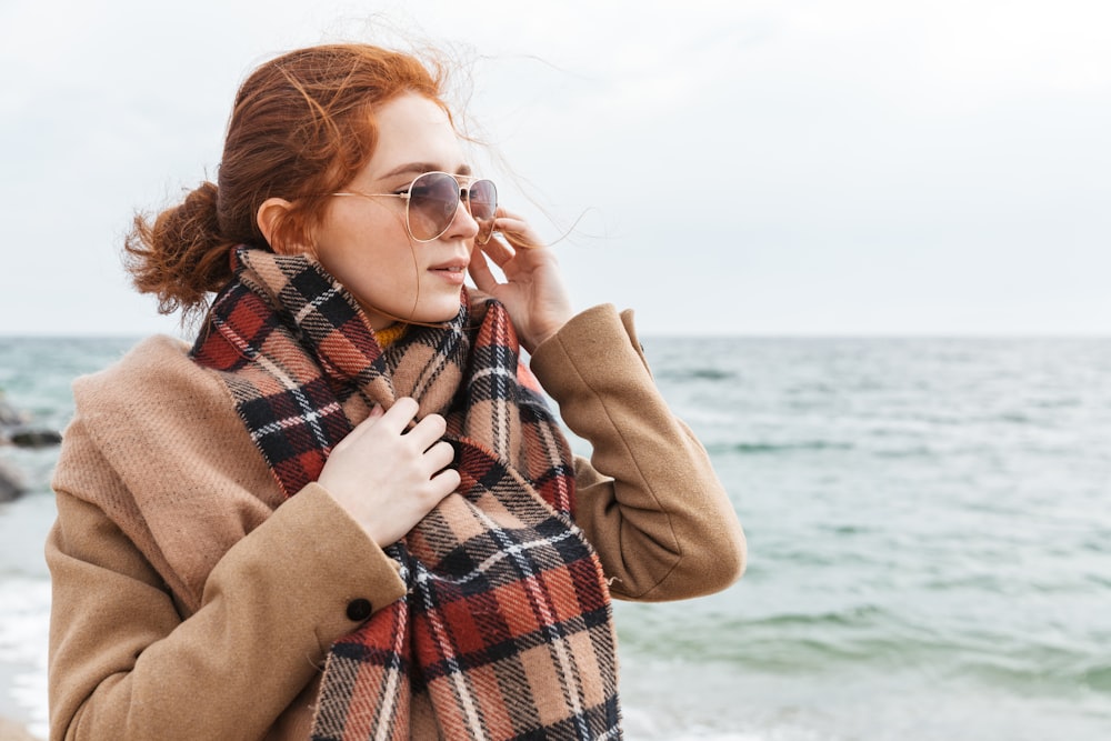 a woman wearing a plaid scarf on the beach