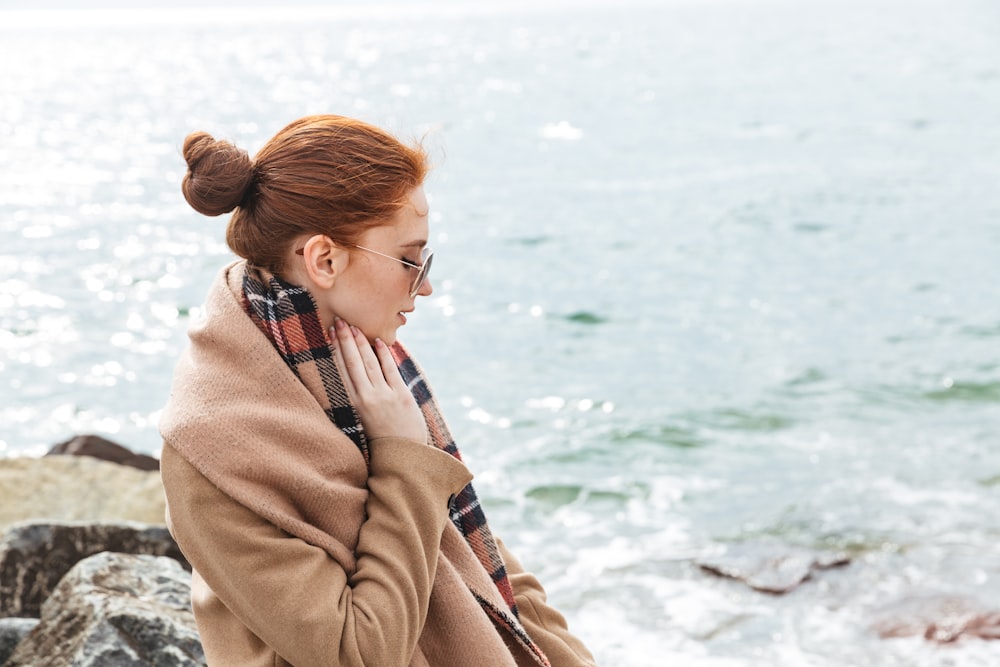 a woman sitting on a rock next to the ocean