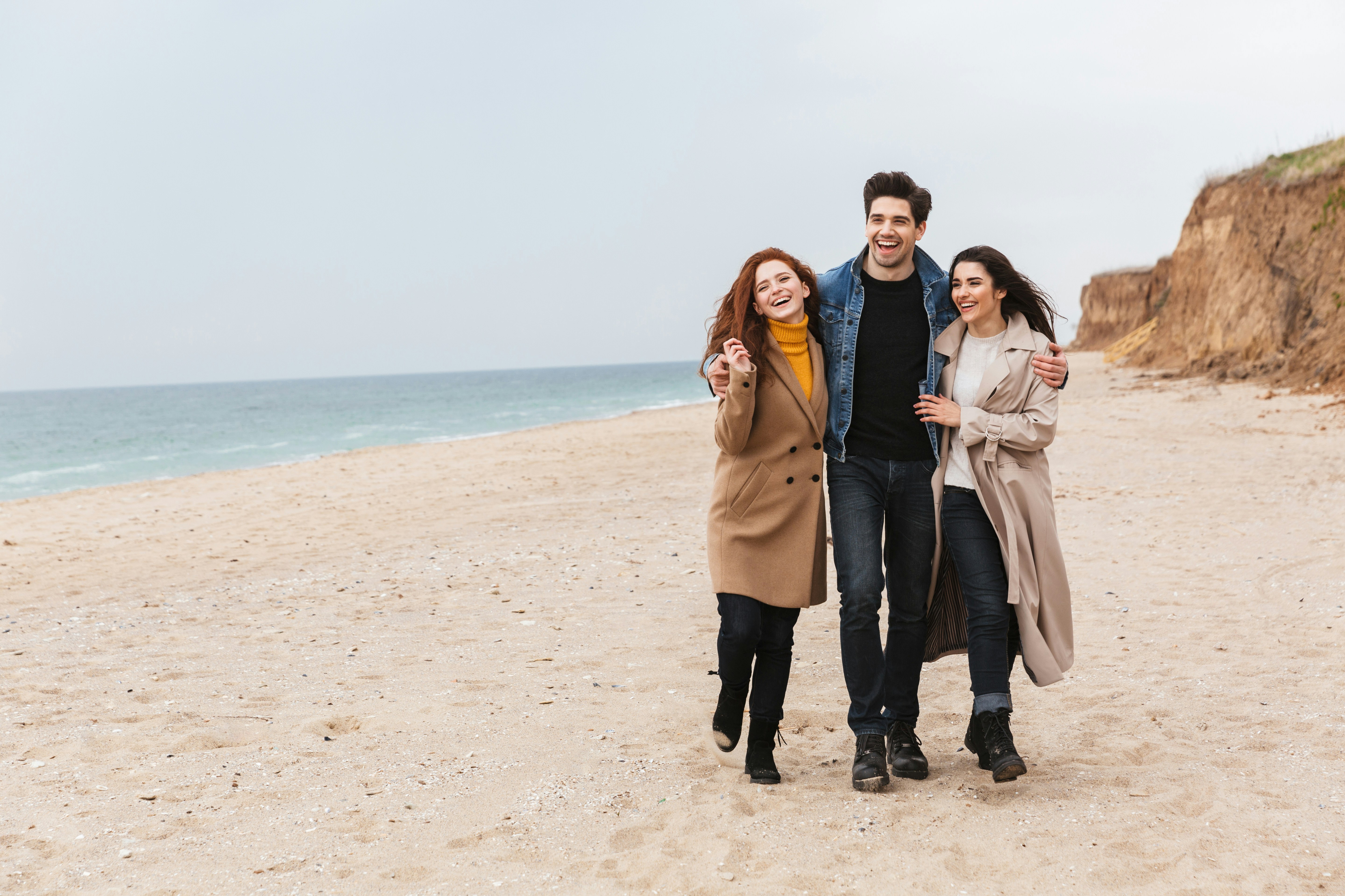 a group of people walking on a beach next to the ocean