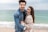 a man and a woman standing on a beach next to the ocean
