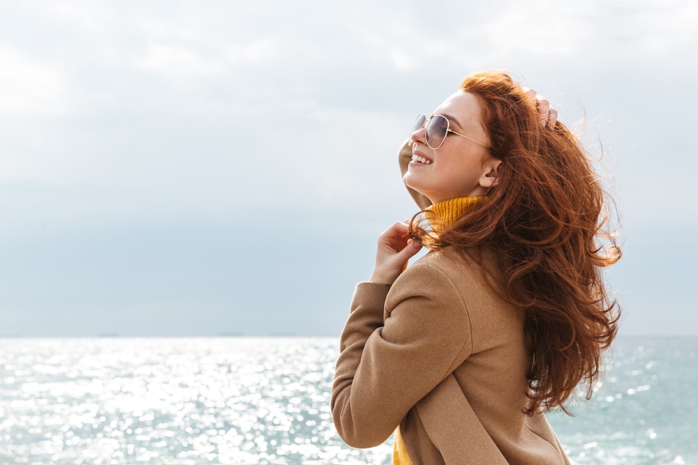 a woman standing on a beach with her hair blowing in the wind