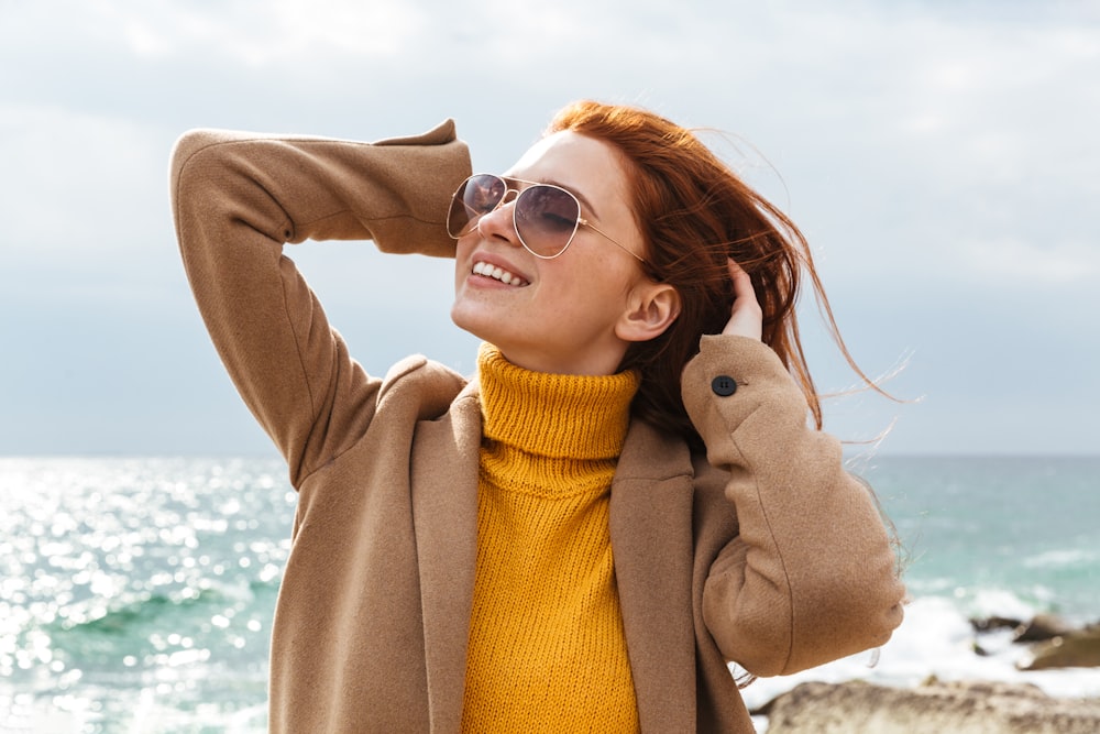 a woman with red hair and sunglasses on a beach