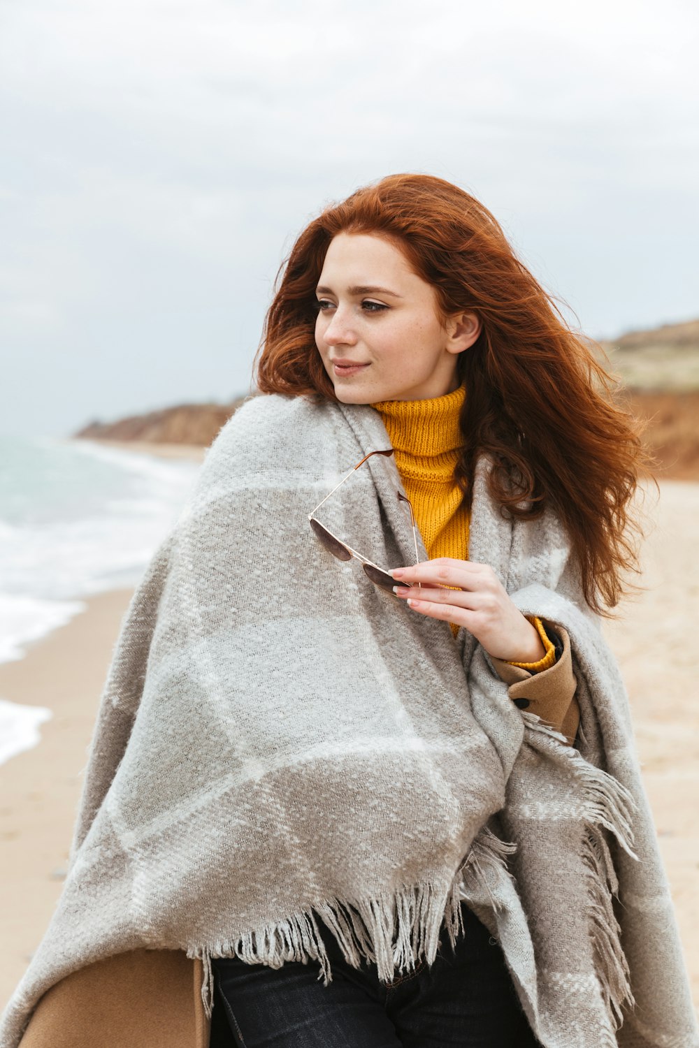 a woman walking down a beach holding a cell phone