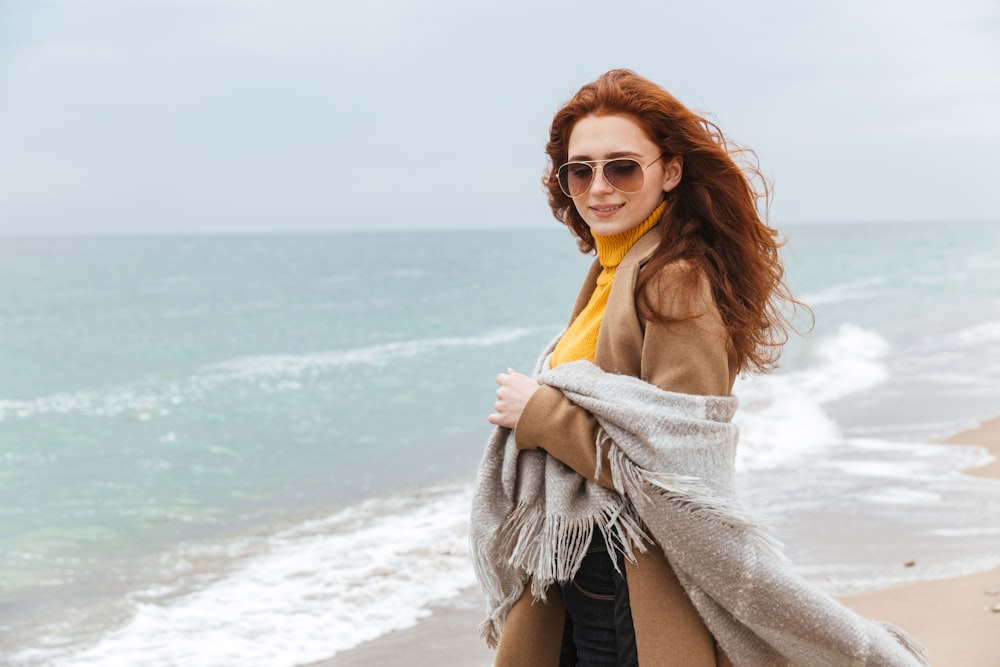 a woman standing on a beach with a scarf around her neck