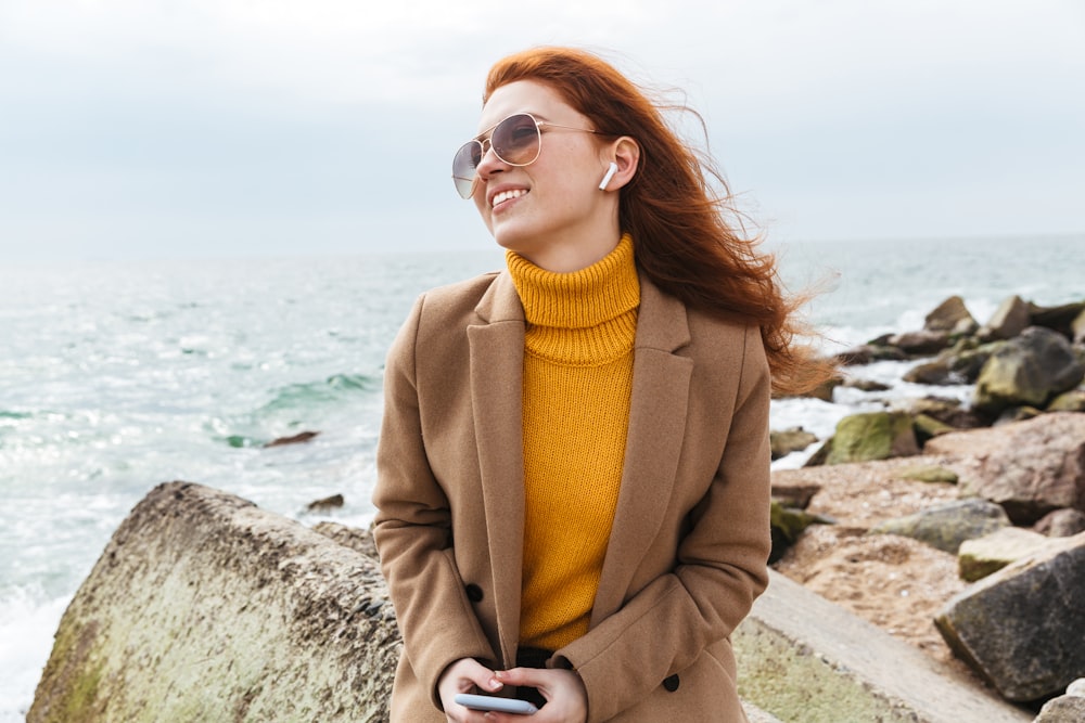 a woman with red hair wearing a coat and holding a cell phone