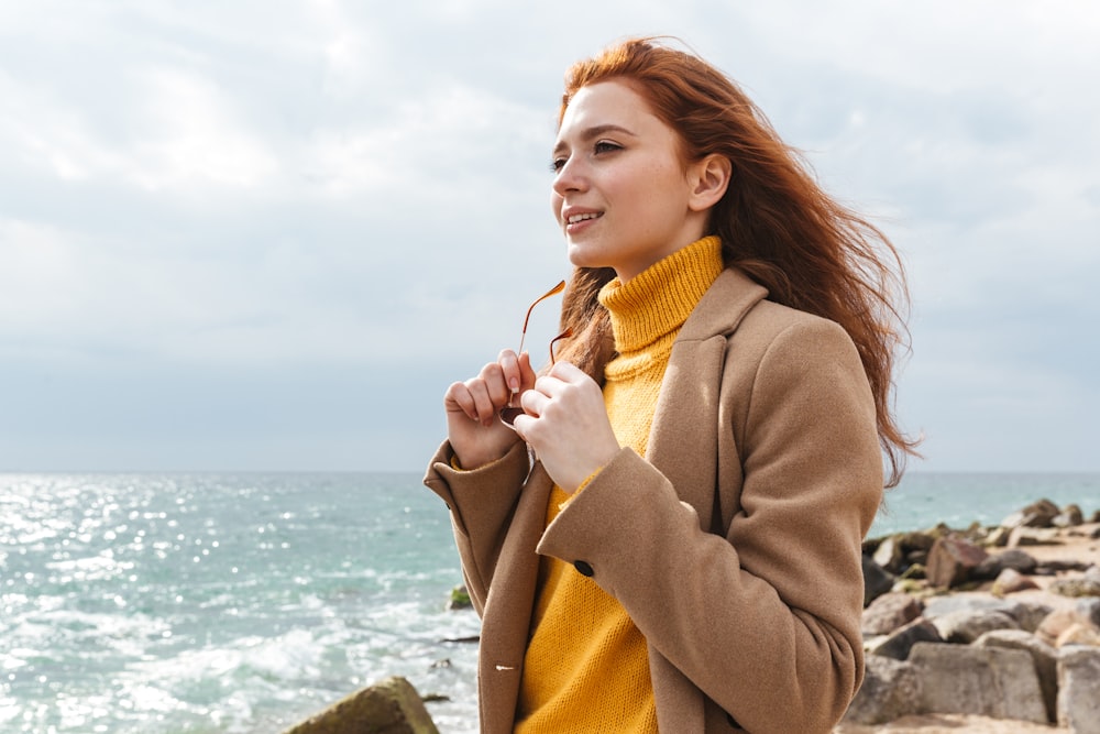 a woman standing on a rocky beach next to the ocean