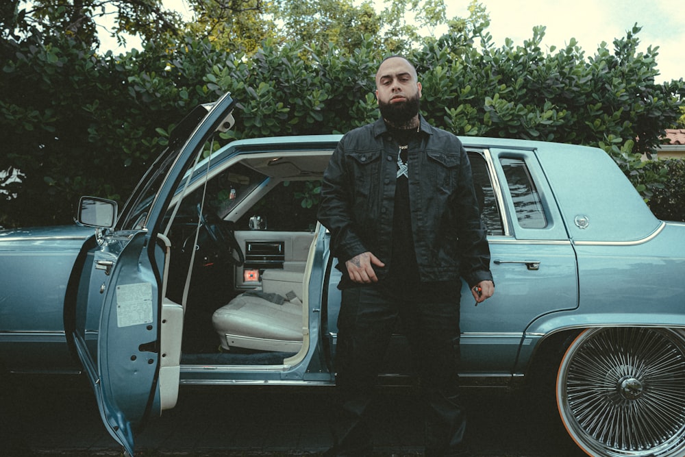 a man standing next to a car with the door open