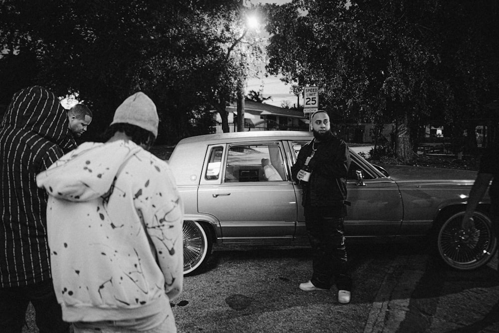 a group of people standing around a parked car