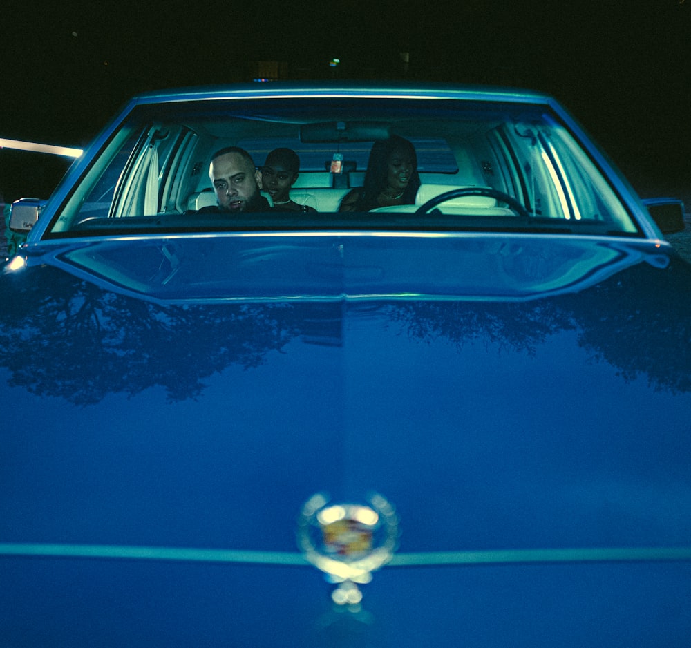 a man and a woman sitting in a blue car