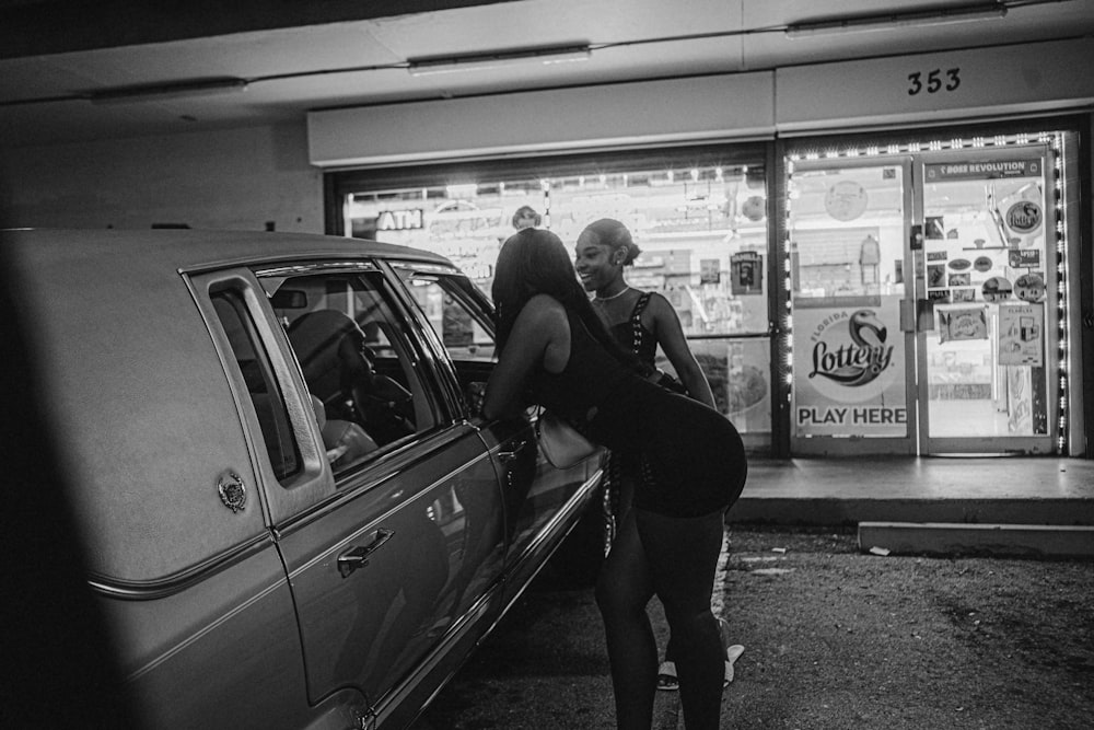 a woman standing next to a car in front of a store