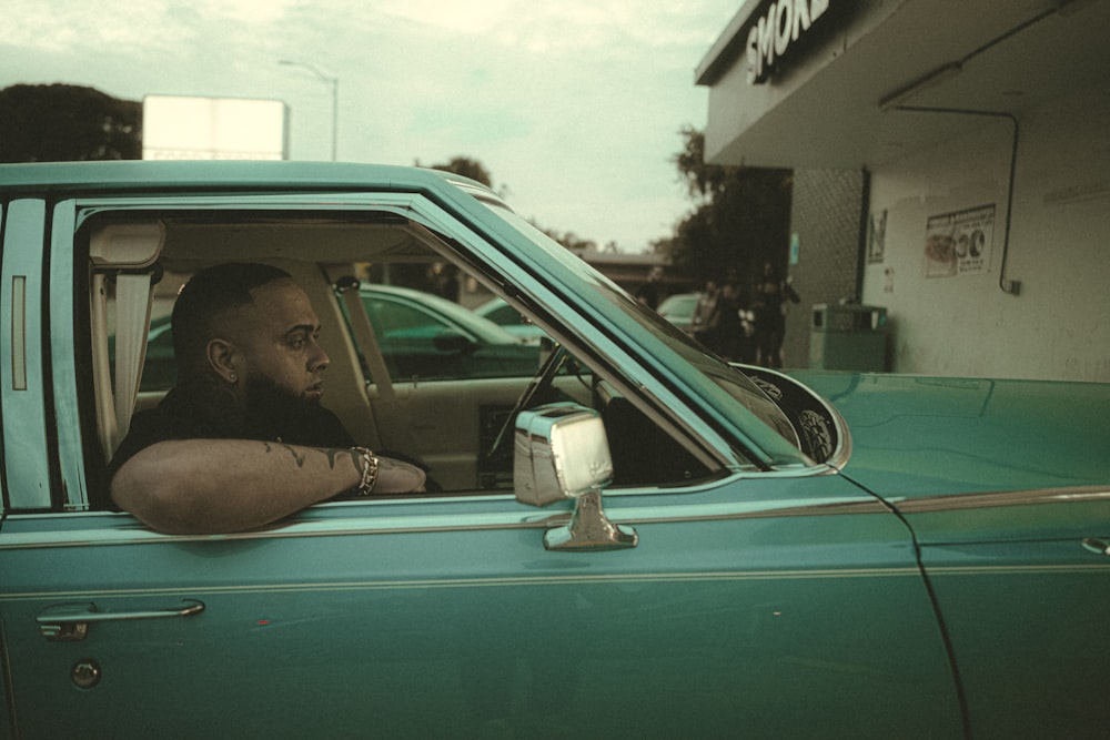 a man sitting in the drivers seat of a green truck