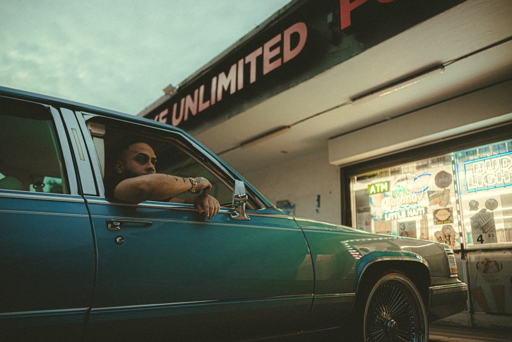 a man is sitting in the driver's seat of a green car