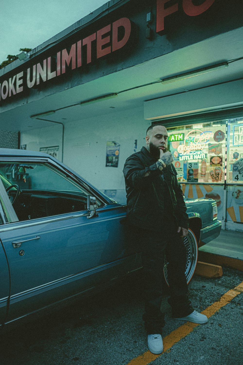 a man standing next to a blue car in front of a store