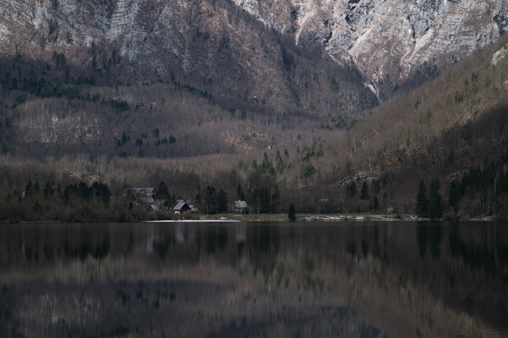 a lake surrounded by mountains with a house in the middle