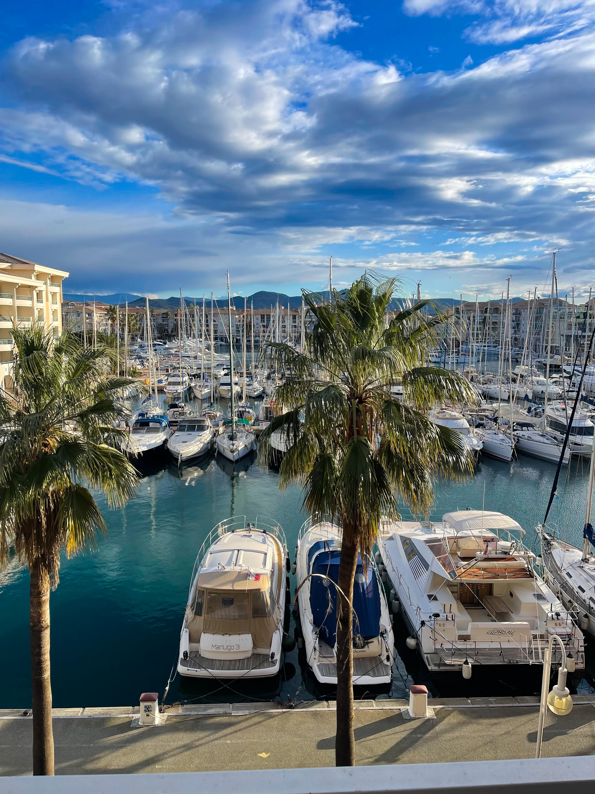 a marina filled with lots of boats under a cloudy blue sky