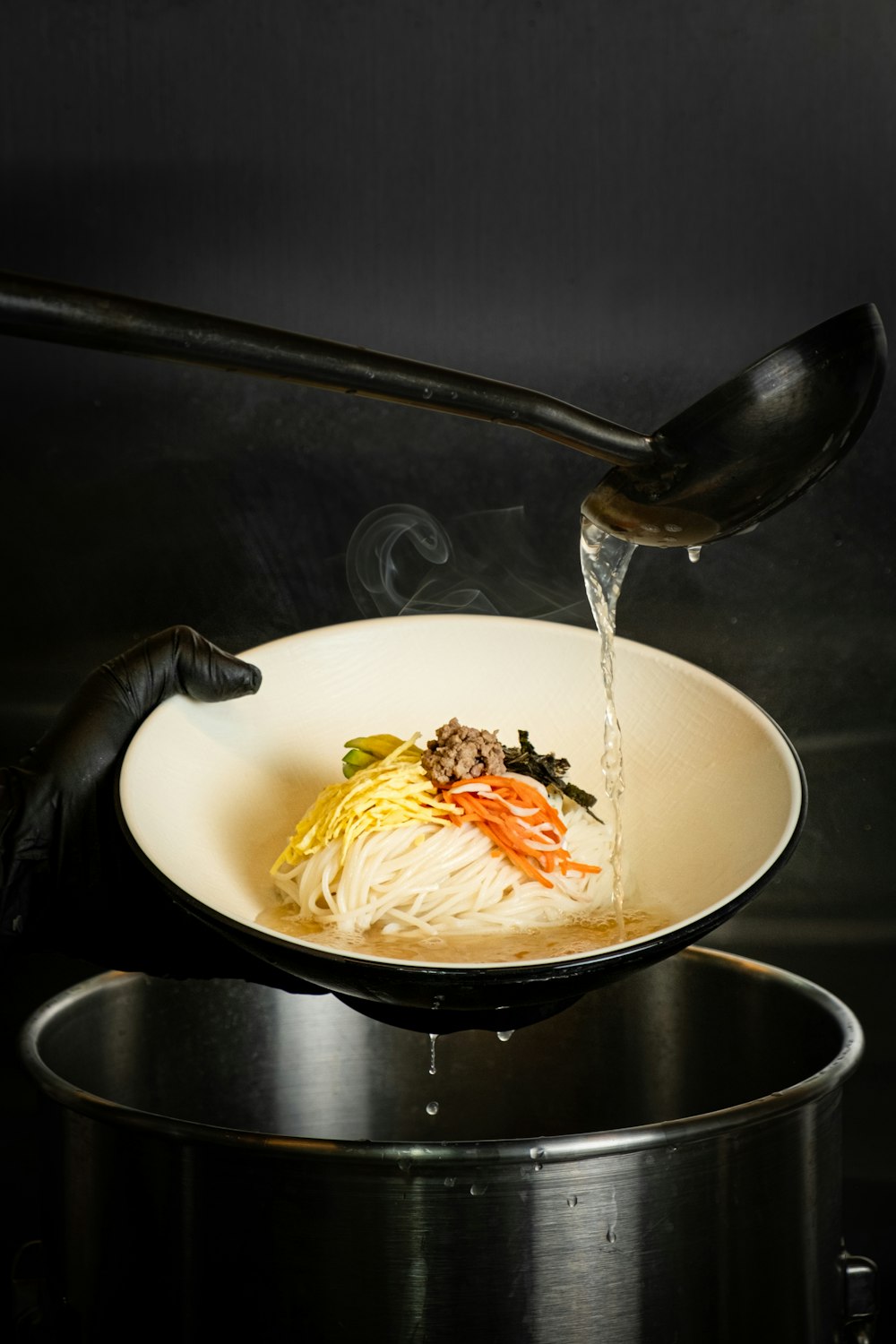 a bowl of noodles being poured into a pot