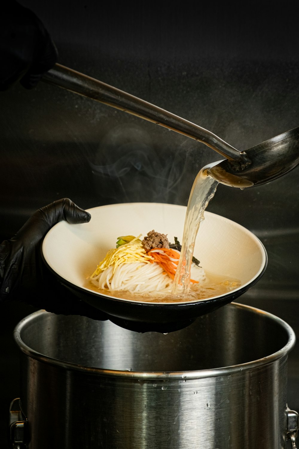 a person pouring a pot of noodles with a ladle