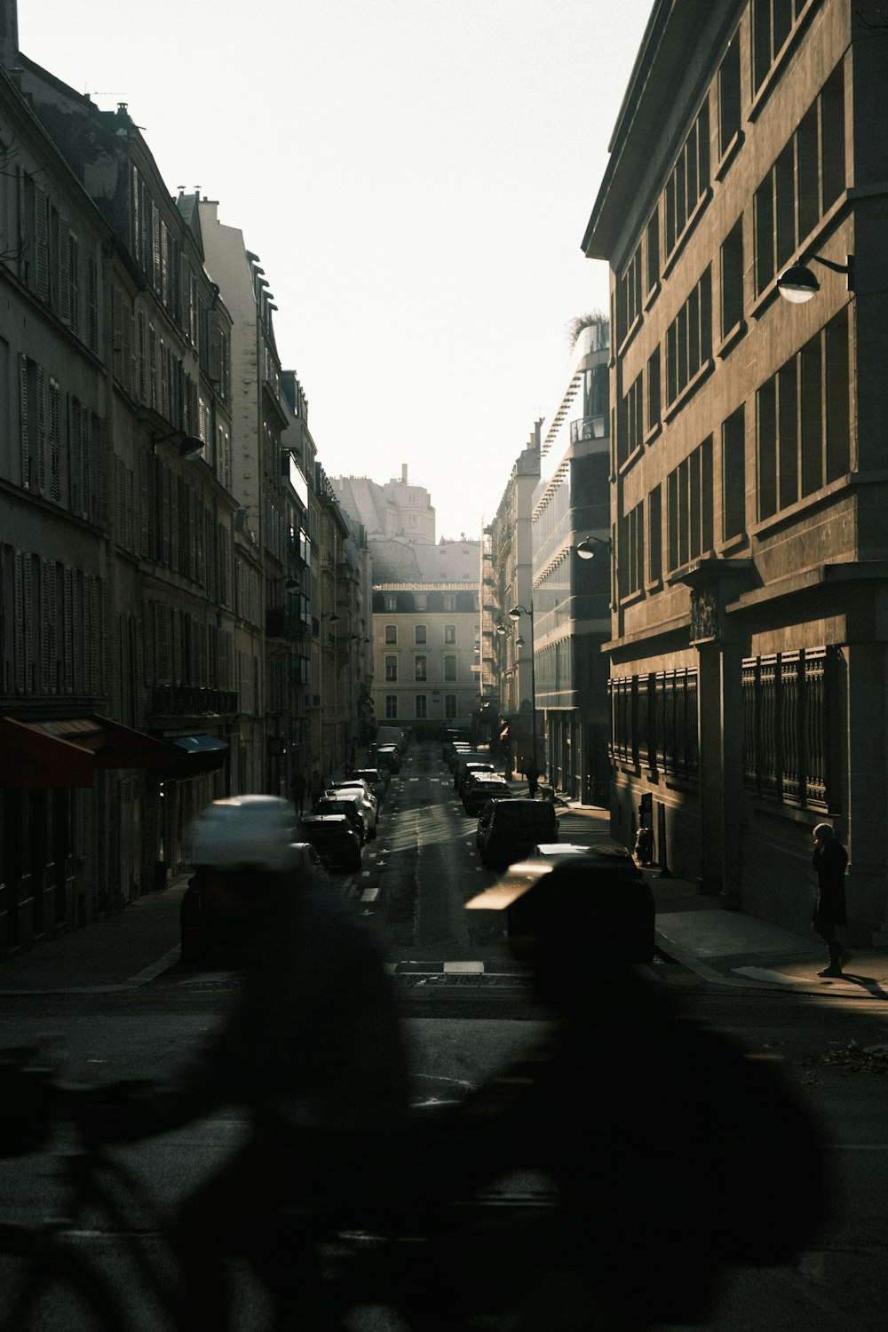 a person riding a bike down a street next to tall buildings