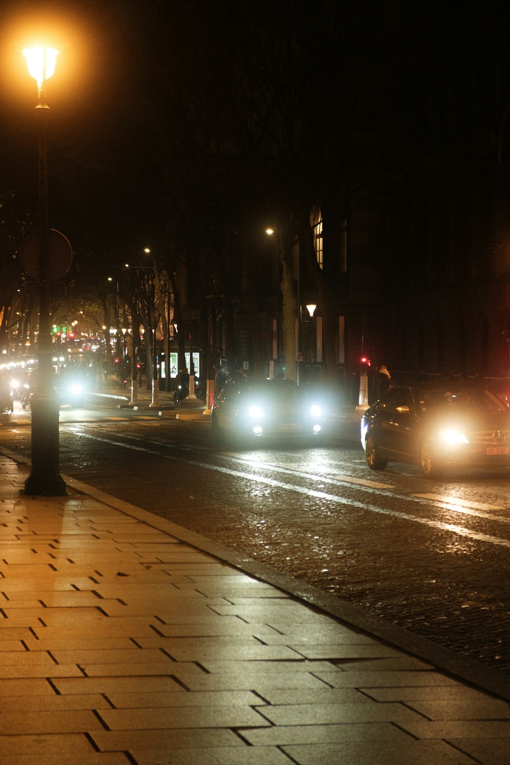 a couple of cars driving down a street at night