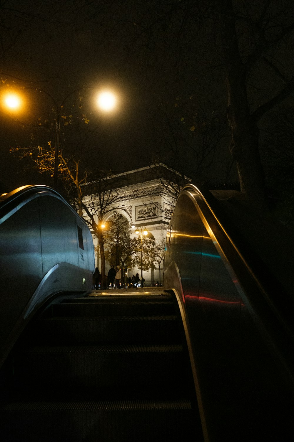 una escalera mecánica por la noche con un edificio al fondo