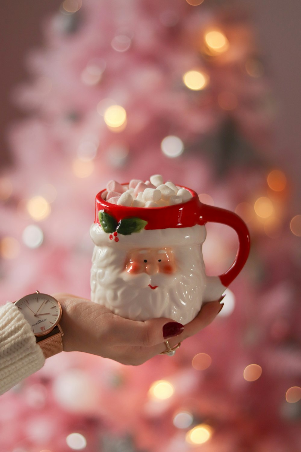 a person holding a coffee mug in front of a christmas tree
