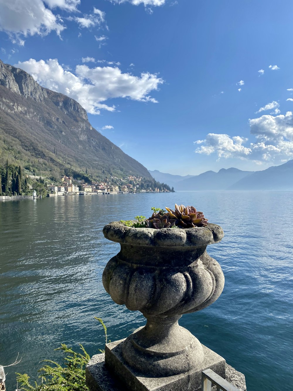 a stone planter sitting on the edge of a lake