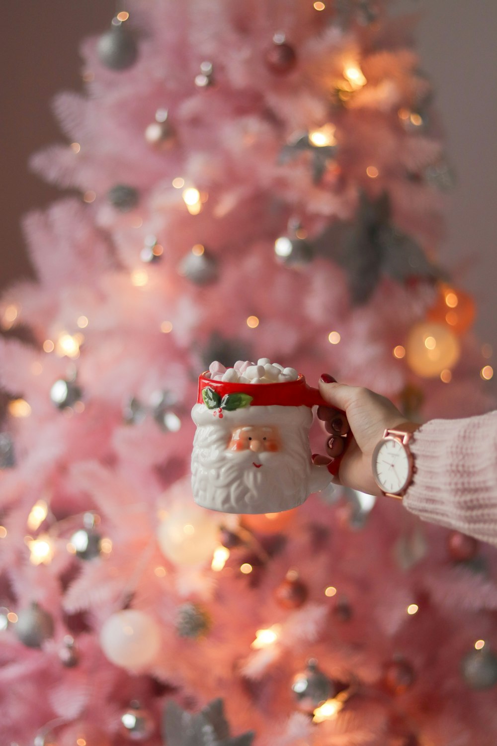 a person holding a mug in front of a pink christmas tree