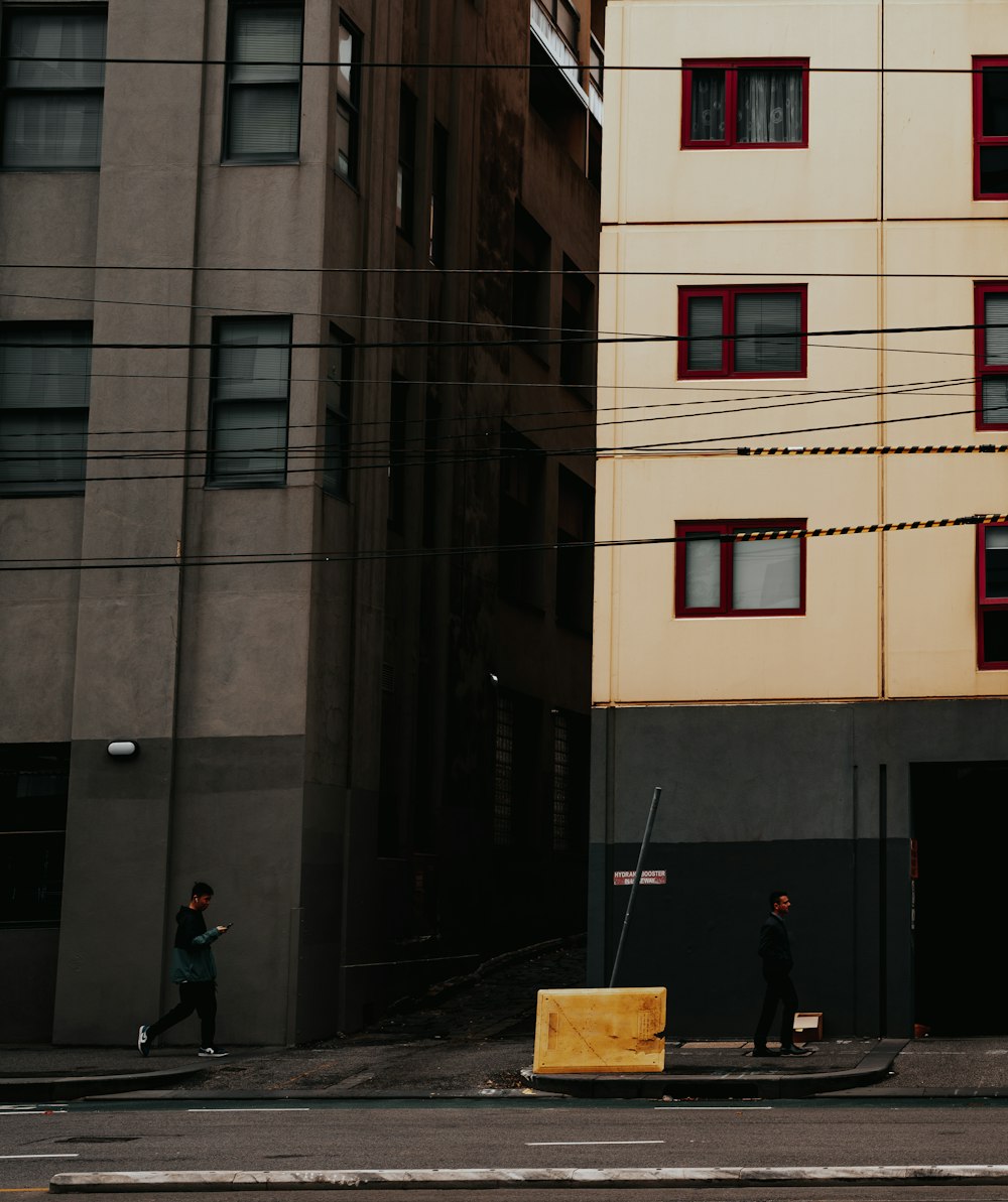 two people walking down a street next to tall buildings