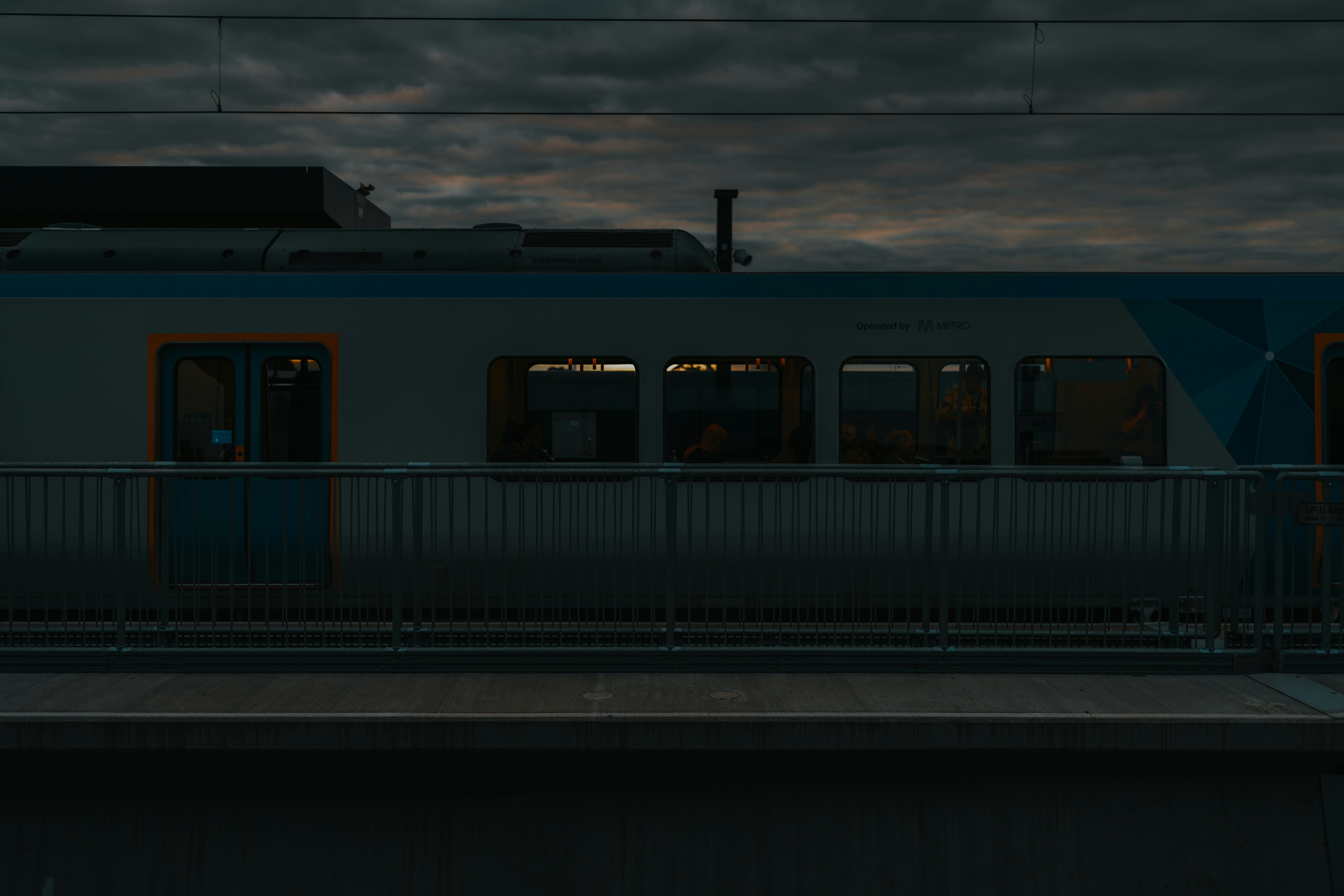 A train traveling past a train station under a cloudy sky