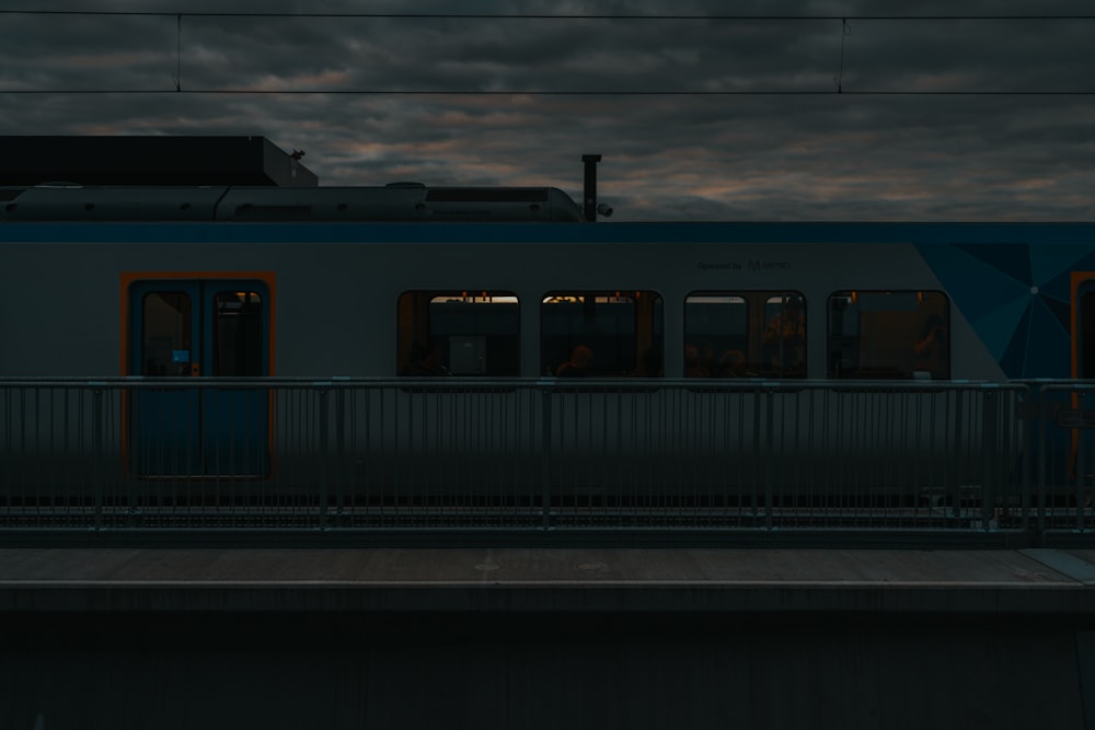 a train traveling past a train station under a cloudy sky