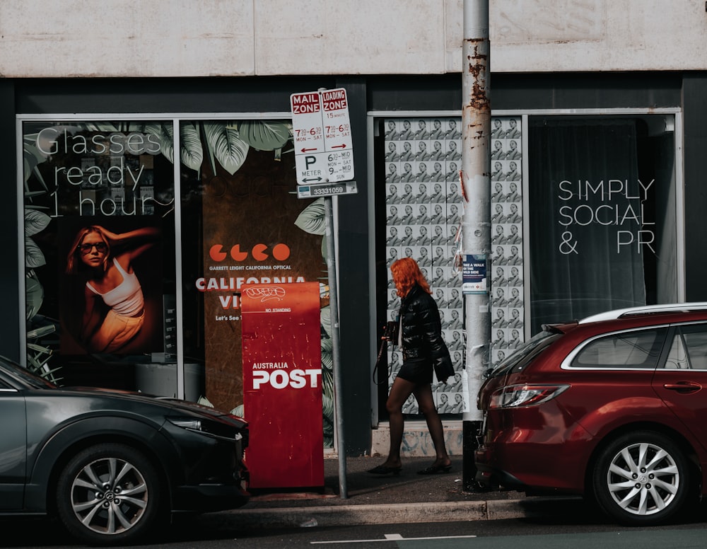 a woman walking down a street past a post office