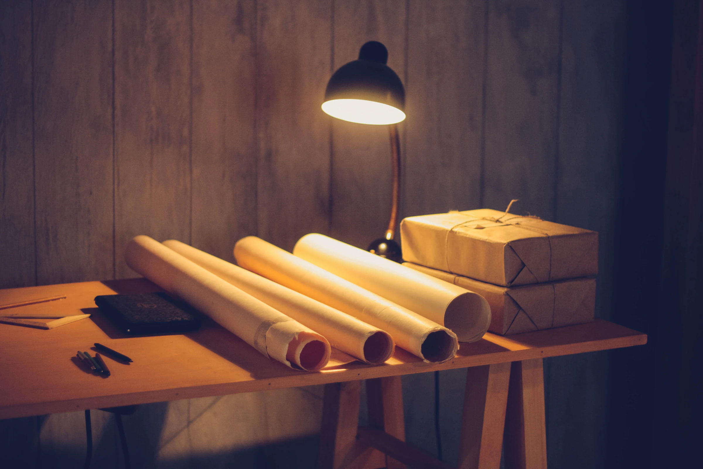 Rolled blueprints under a warm desk lamp