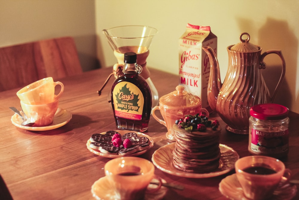 a wooden table topped with cups and saucers