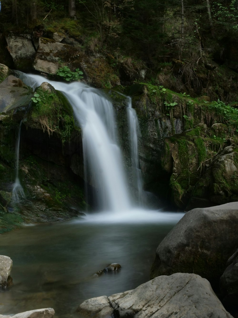 a small waterfall in the middle of a forest