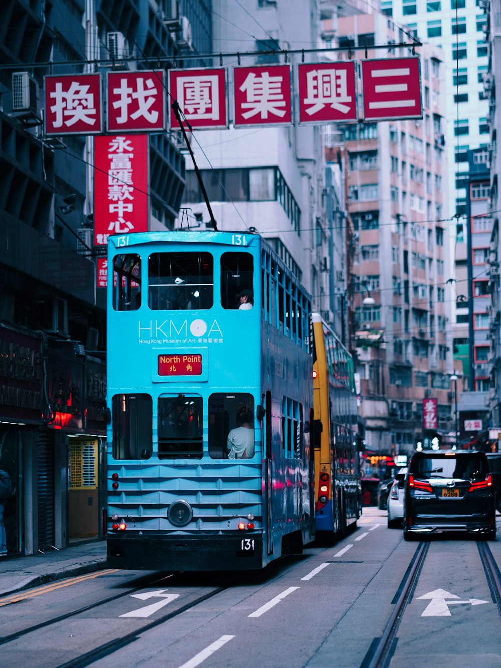 a blue double decker bus driving down a street