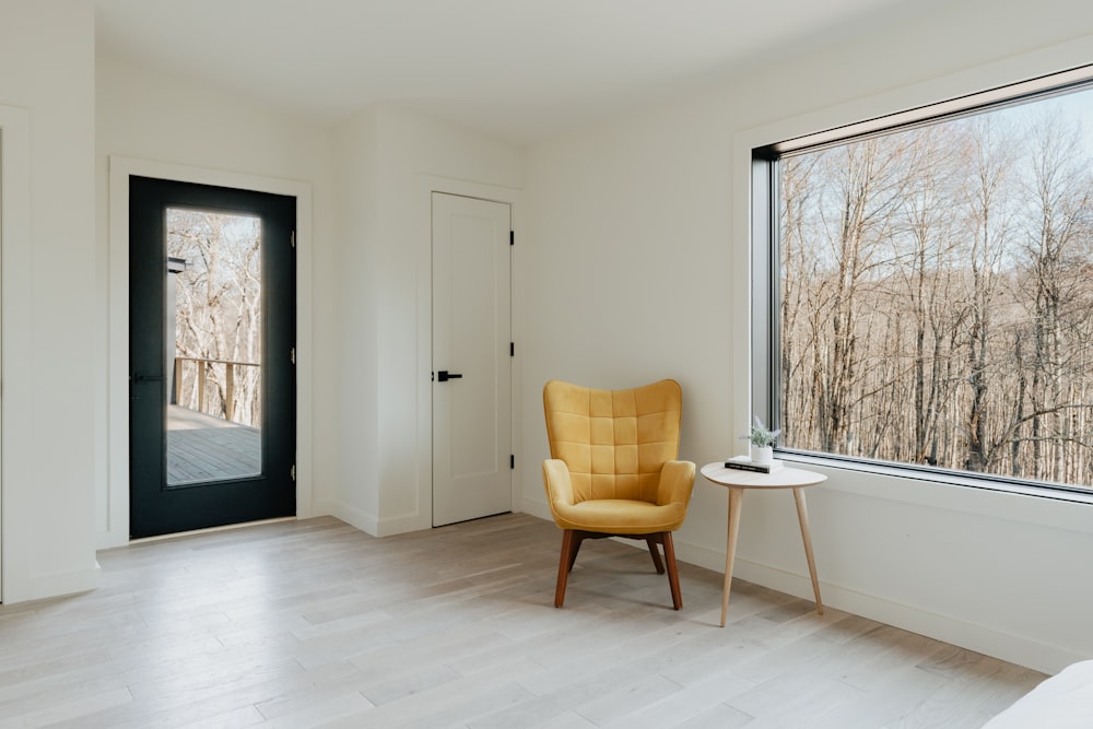 uma cadeira amarela sentada em uma sala ao lado de uma janela