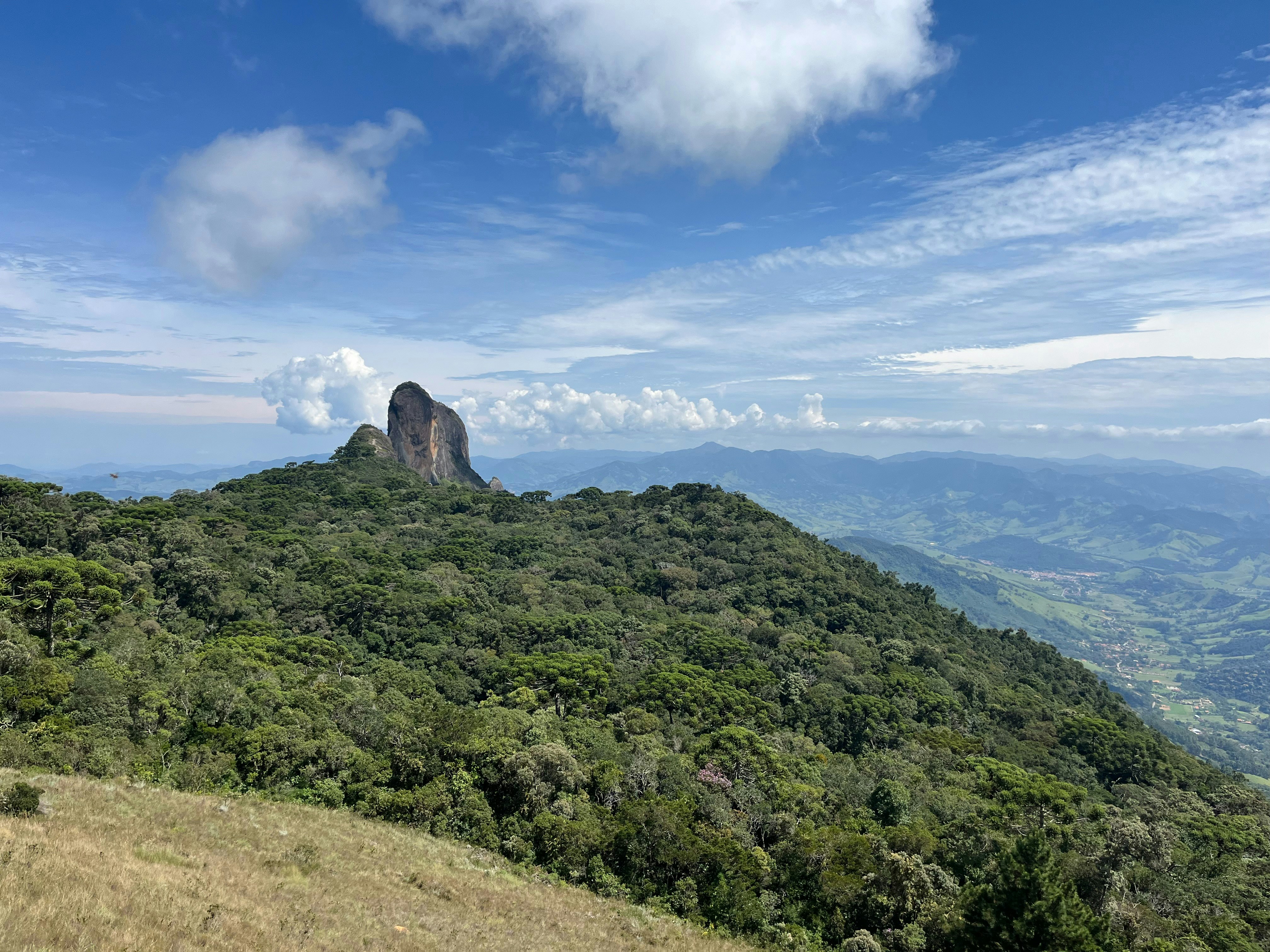 a view of a mountain with trees and mountains in the background
