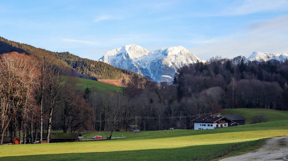 a house in the middle of a field with mountains in the background