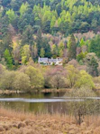 a house sits on a hill above a lake
