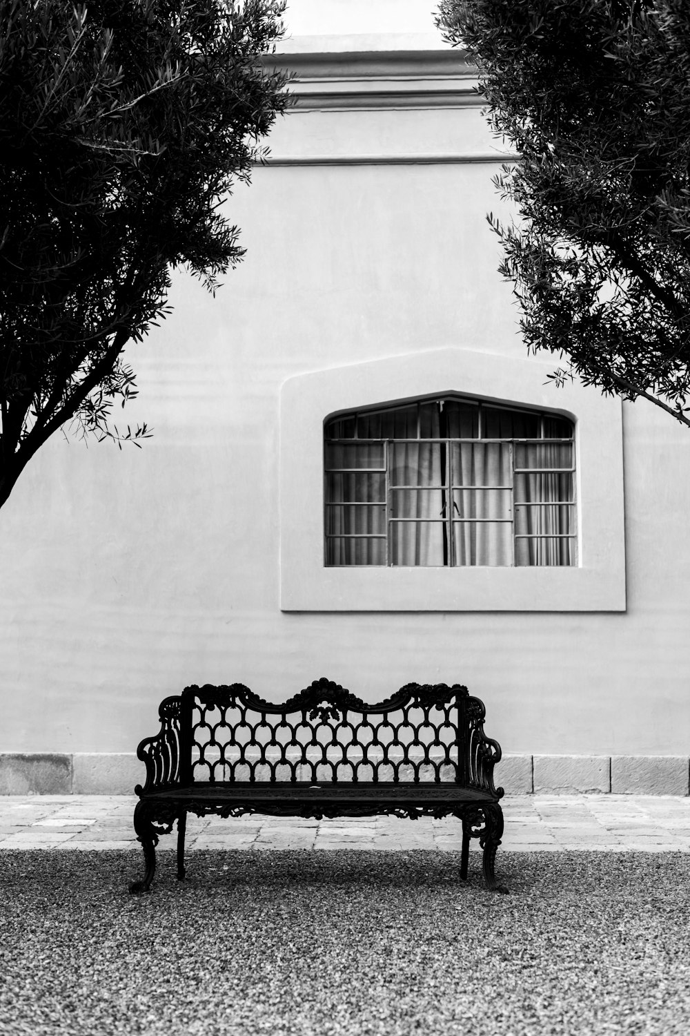 Una foto in bianco e nero di una panchina di fronte a un edificio