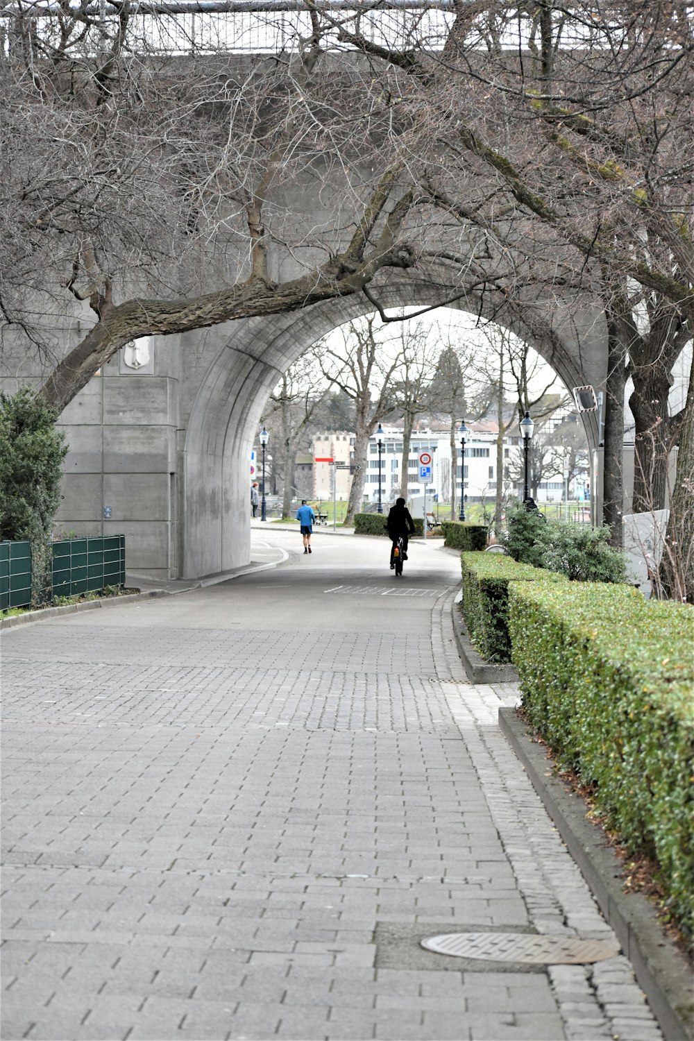 a person walking down a sidewalk under a bridge