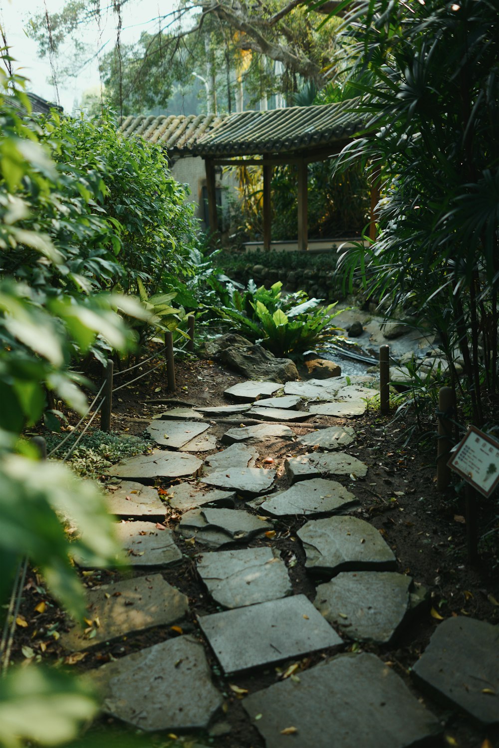 un sentiero in pietra in un giardino con un gazebo sullo sfondo