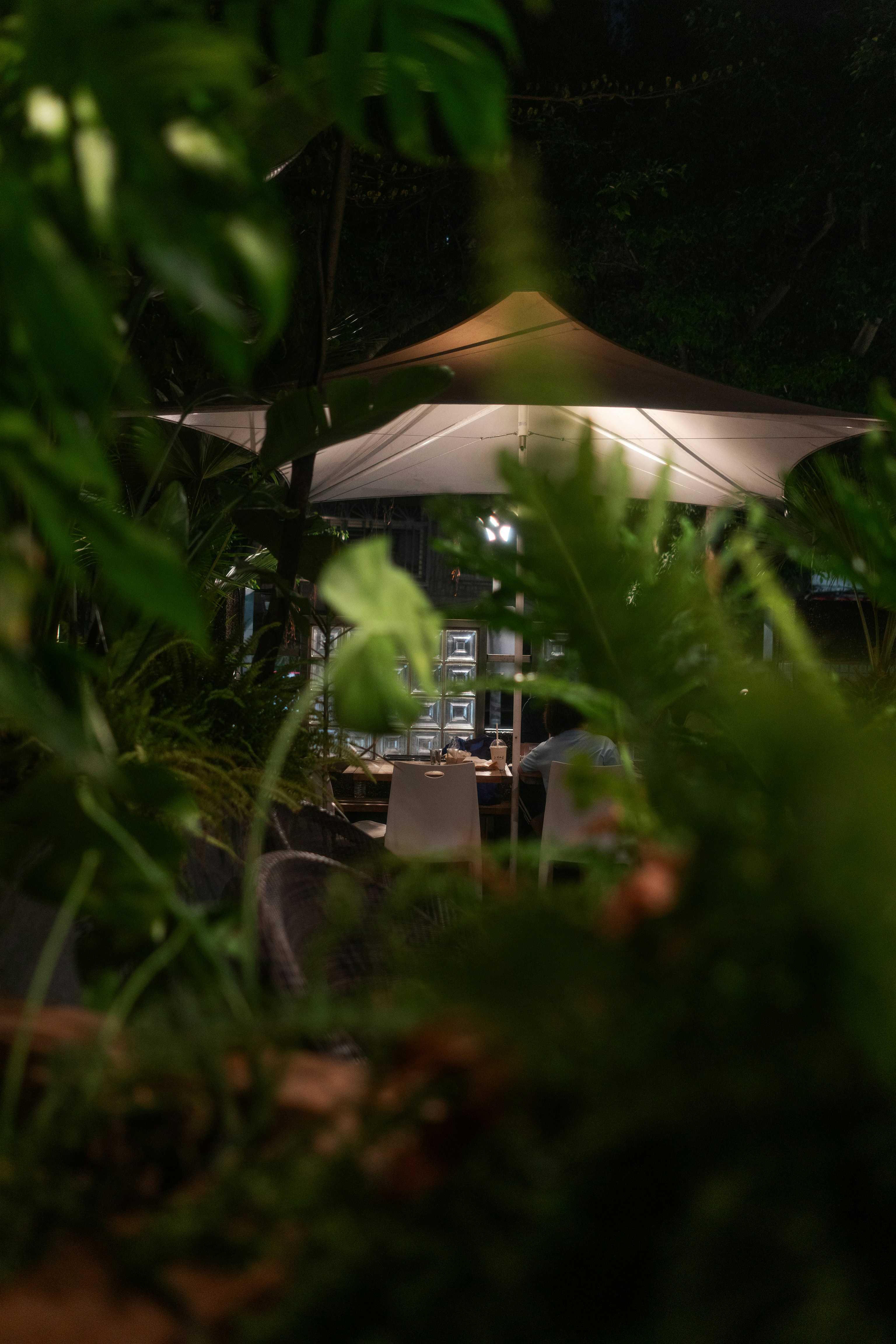 a table with a white umbrella in the middle of a forest