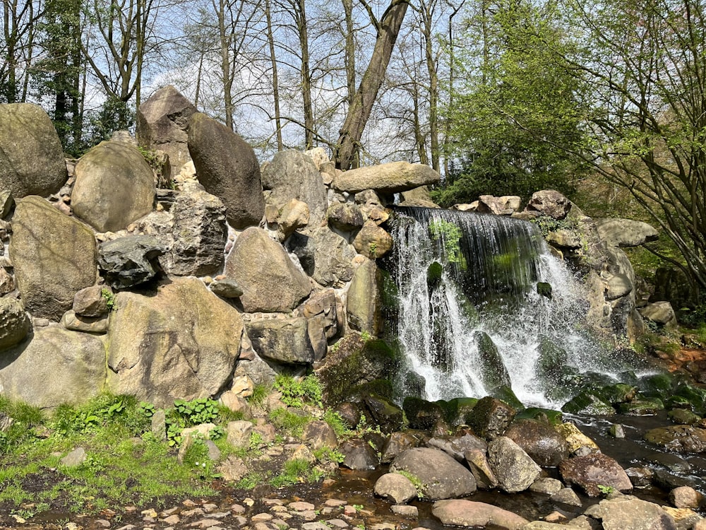 ein Wasserfall, umgeben von Felsen und Bäumen