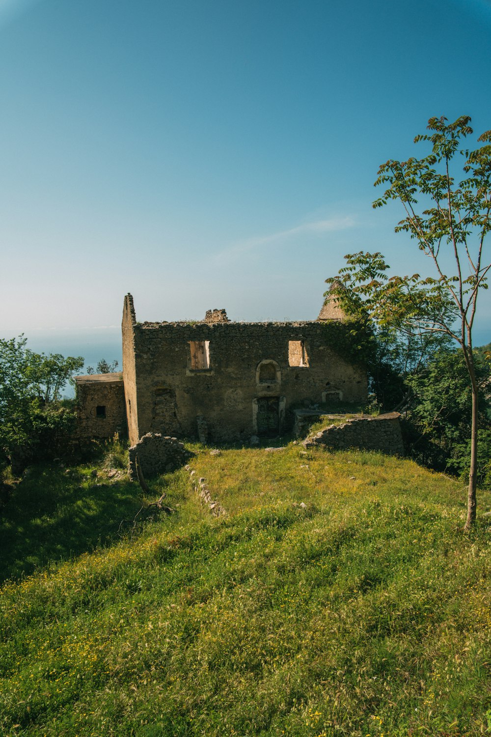 a stone building sitting on top of a lush green hillside