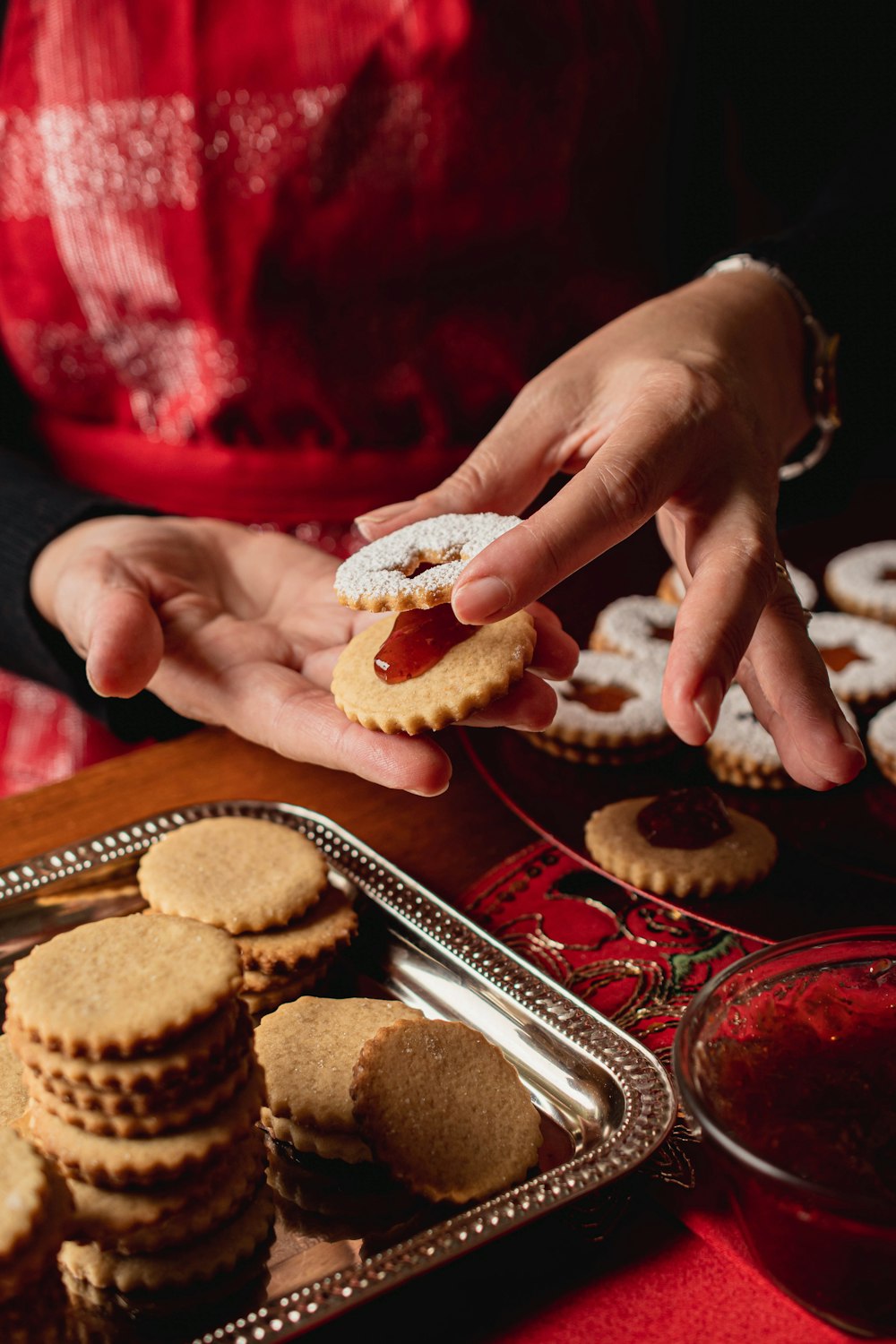 a person holding a cookie in front of a tray of cookies
