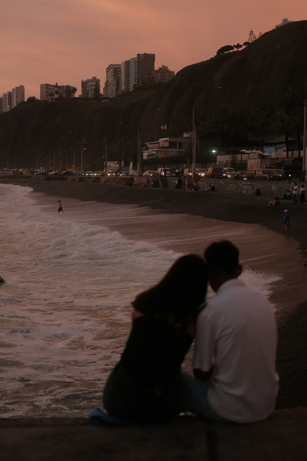 a man and woman sitting on the edge of a beach