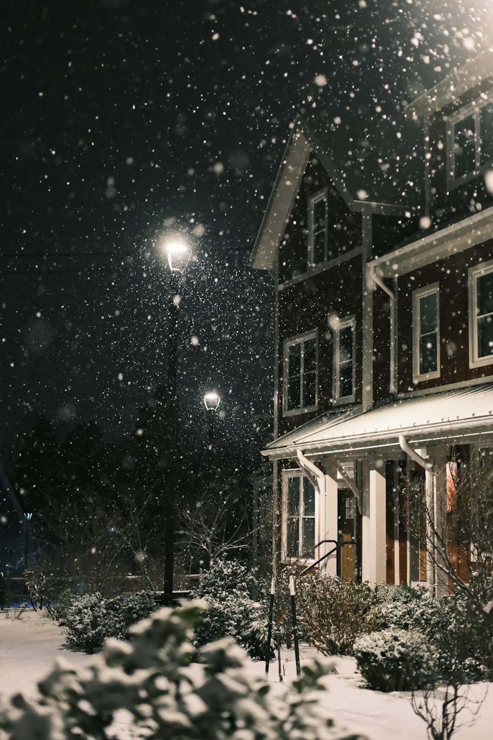 a snow covered street light in front of a house